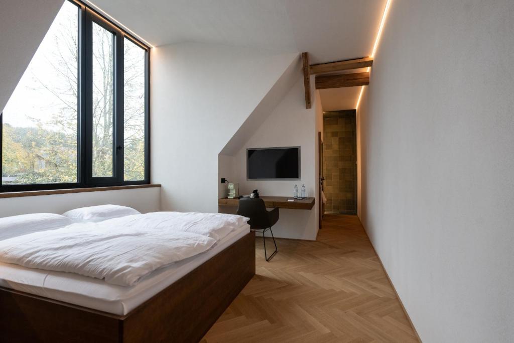 a bedroom with a bed and a desk and a tv at Lukas Kapeller Hotel und Restaurant in Steyr