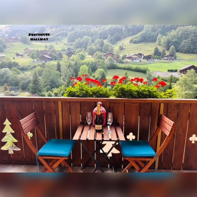 uma mesa de madeira com uma garrafa de vinho e 2 cadeiras em Deluxe Penthouse in the Swiss Alps em Val dʼIlliez