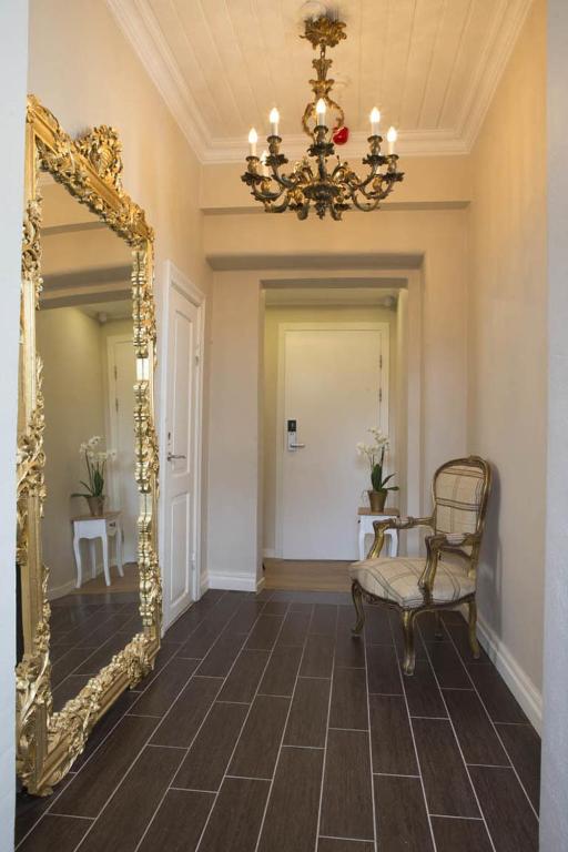 un corridoio con specchio, sedia e lampadario a braccio di Sockerslottet Hotell a Kristinehamn