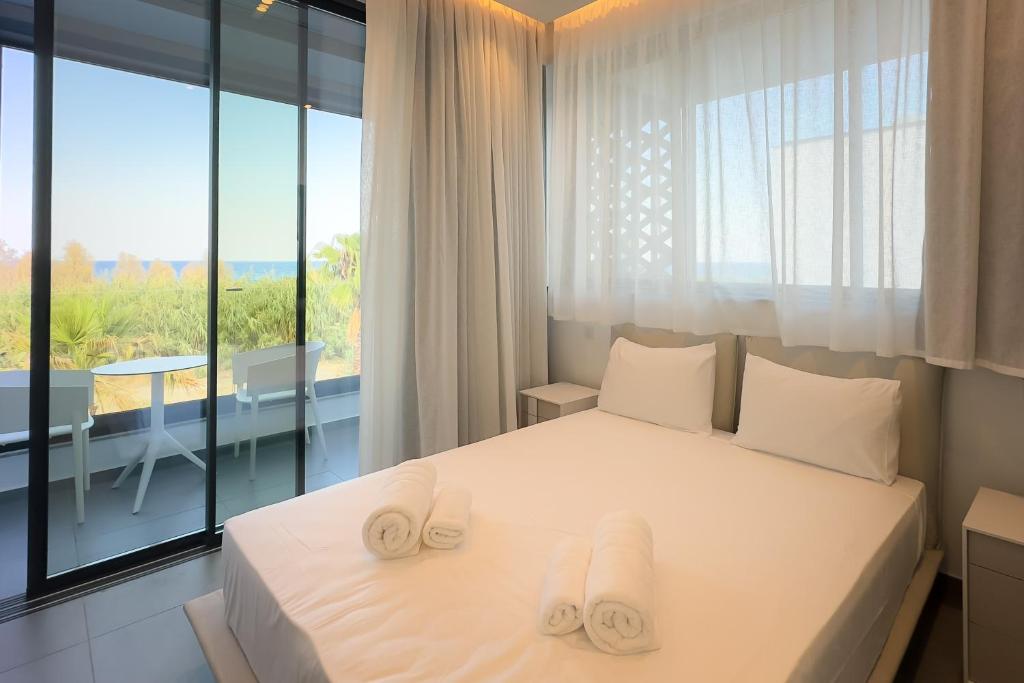 ein Schlafzimmer mit einem weißen Bett mit Handtüchern darauf in der Unterkunft Sunrise Beachfront Villas - Villa 3 in Paralimni