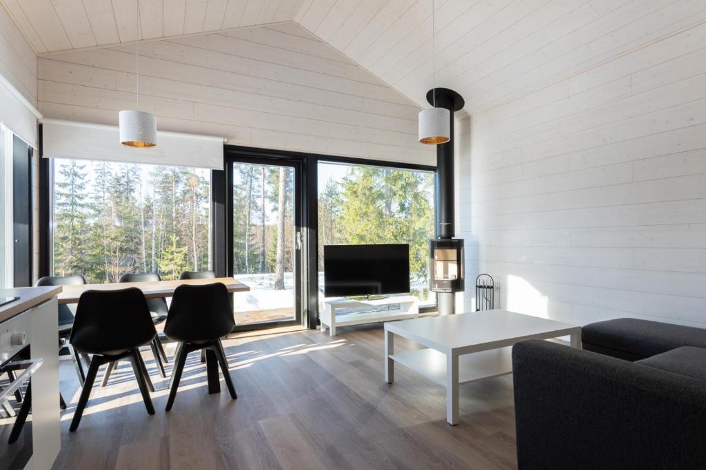 a living room with a table and chairs and a television at Himoskuutio 6 inc outdoor jacuzzi in Jämsä