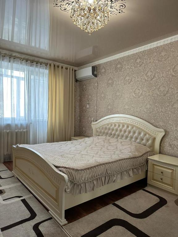 een slaapkamer met een wit bed en een kroonluchter bij Квартира люкс in Taraz
