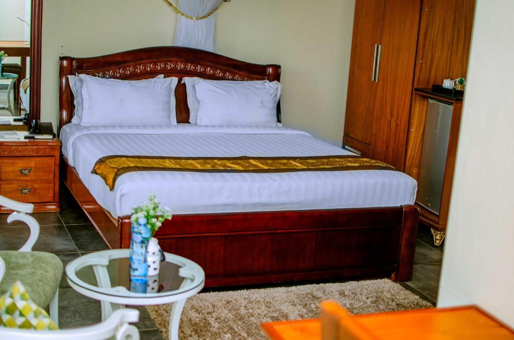 um quarto com uma cama, uma mesa e uma cadeira em La Grande Hotel em Kampala