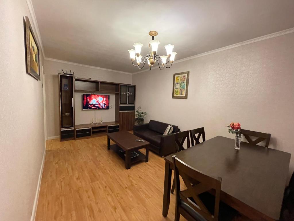 een woonkamer met een tafel, een bank en een televisie bij Two-Bedroom Apartment in Ulaanbaatar