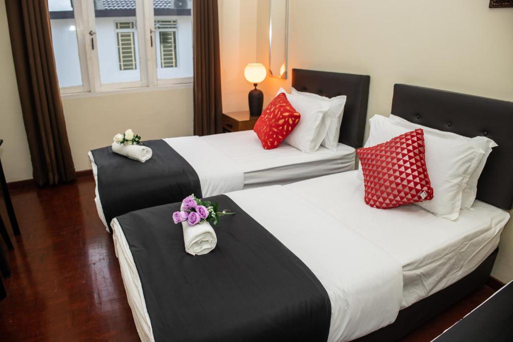 two beds in a hotel room with red and white pillows at Sweet Inn Guest House in Kuantan