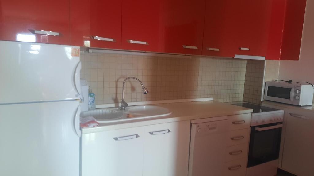 uma cozinha com um lavatório branco e armários vermelhos em Luxury apartment em Skopje