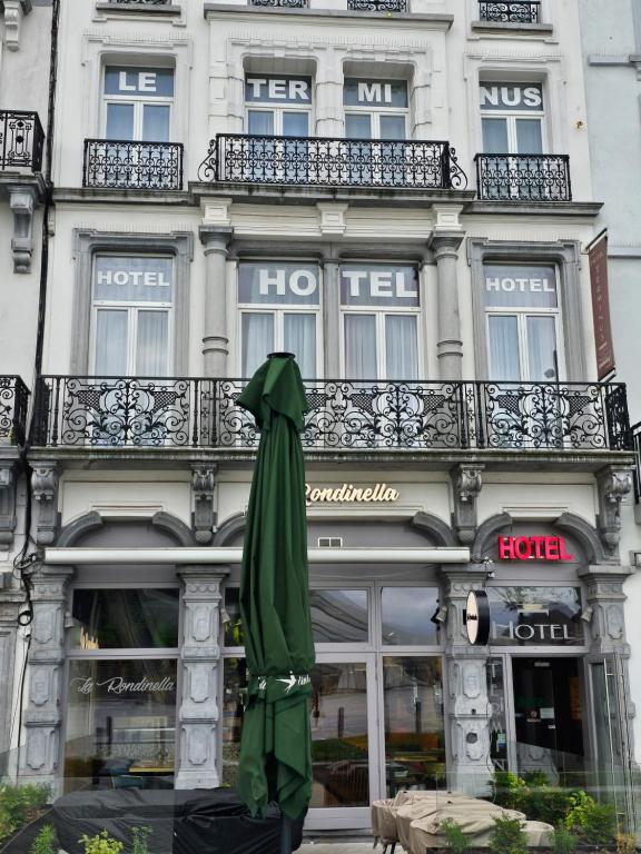 una sombrilla verde cerrada frente a un edificio en Hotel Le Terminus, en Mons
