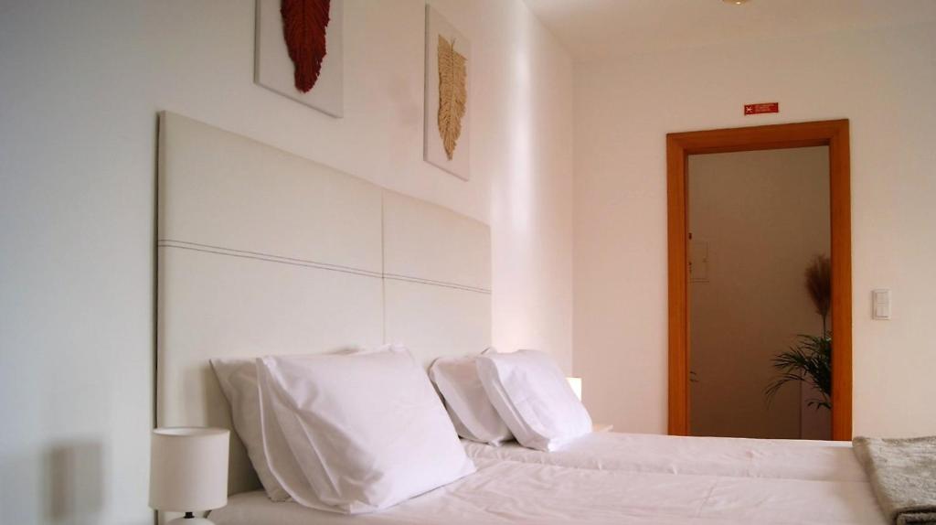 um quarto branco com 2 camas e almofadas brancas em Studio no centro do Funchal em Funchal