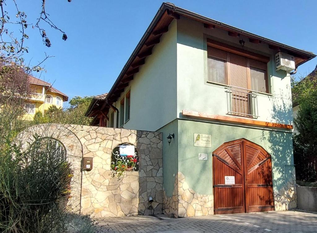 una casa con una puerta marrón y una pared de piedra en Zöldike Vendégház en Kaposvár