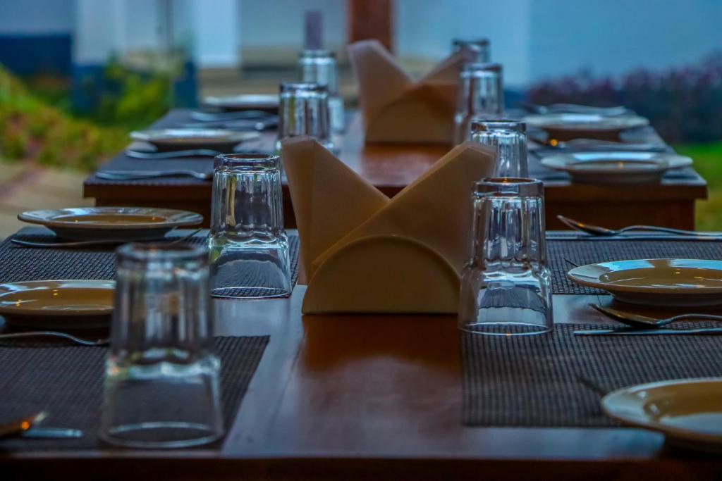 a long wooden table with plates and glasses on it at Winter Note Resorts in Munnar