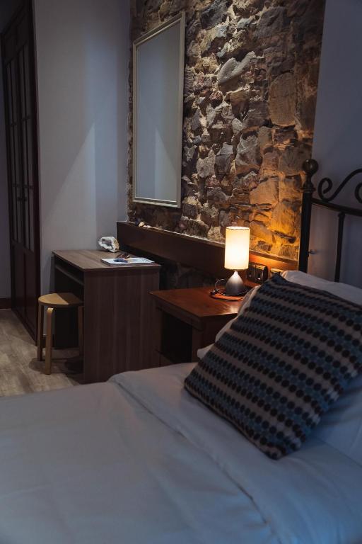 a bedroom with a bed with a lamp and a stone wall at San Sebastián DOT Rooms in San Sebastián
