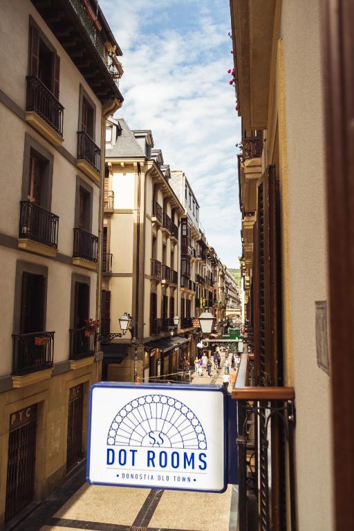 a sign on a fence in a street with buildings at San Sebastián DOT Rooms in San Sebastián