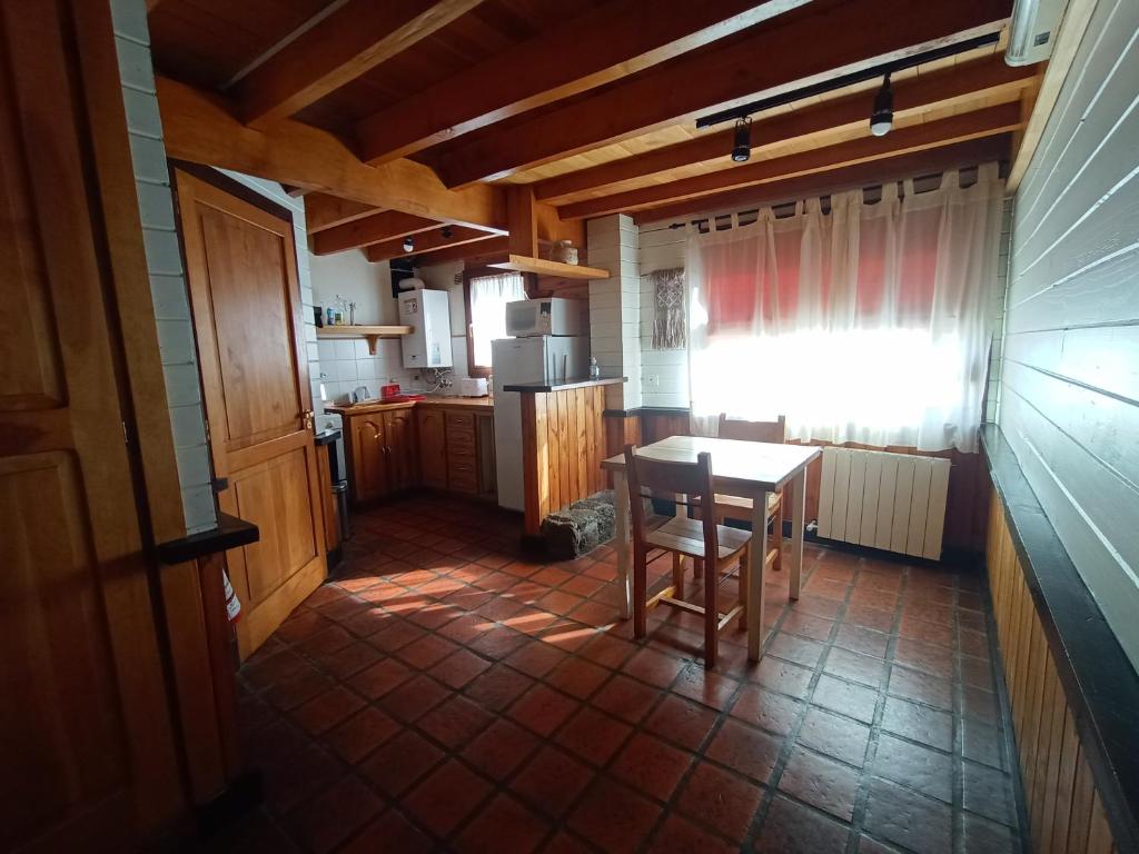 una pequeña cocina con mesa y ventana en Alojamiento Los Huillines en San Martín de los Andes