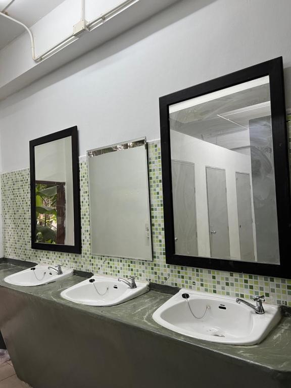 two sinks in a public bathroom with two mirrors at Hostel in Phra Ae beach
