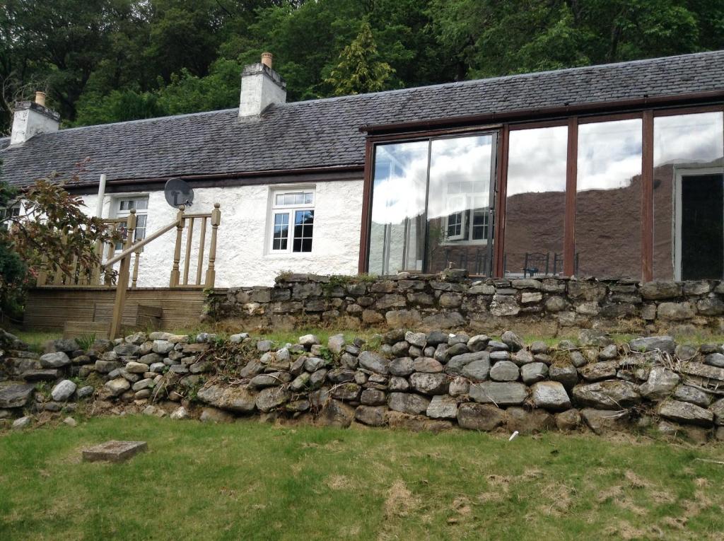 a stone retaining wall in front of a house at Darroch View Cottage in Invermoriston