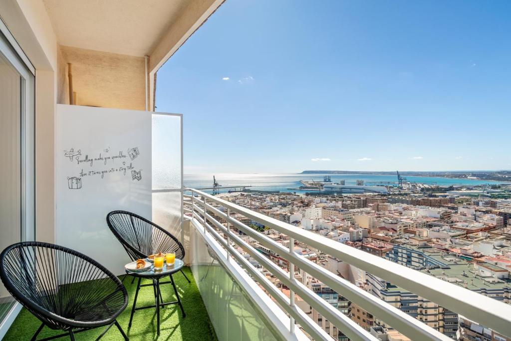 a balcony with two chairs and a view of a city at Sky Suites Alicante in Alicante