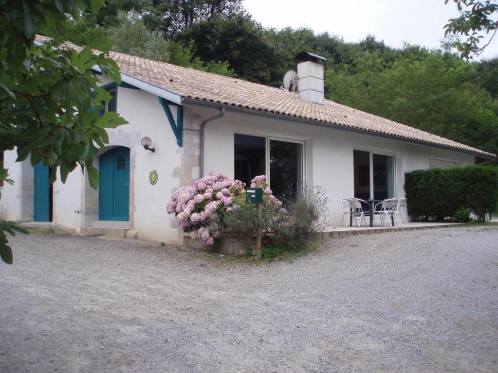 a small white house with a blue door and flowers at Les barthes in Orist