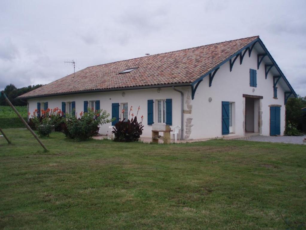 a white house with blue windows and a yard at Le tuc in Orist