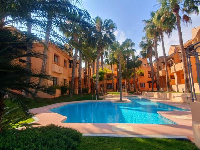 une grande piscine avec des palmiers et des bâtiments dans l'établissement Pure Beach Penthouse & Swimming pool, 3 bedrooms, à Los Alcázares