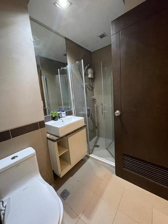 a bathroom with a toilet and a shower and a sink at Admiral Baysuites 1 BR Unit in Manila