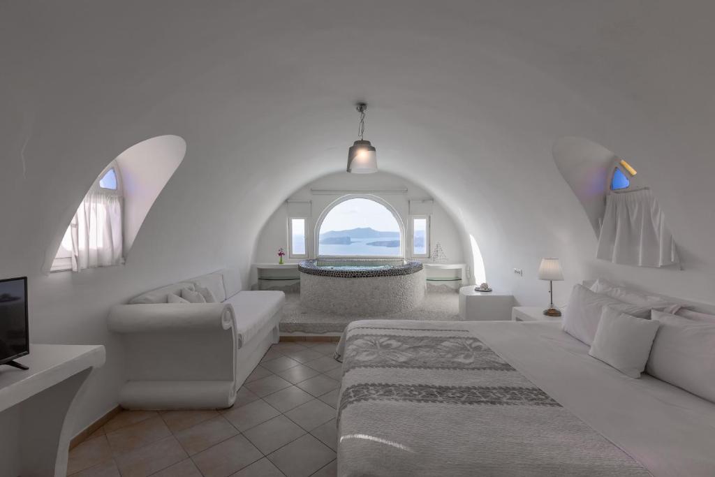 a white living room with a large bed and a tub at Caldera View Private Villa in Megalochori