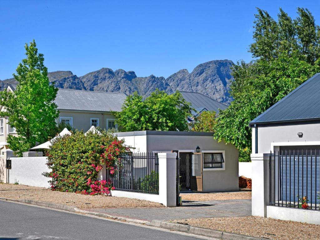 een huis met een hek en bergen op de achtergrond bij La Rochelle Cottage in Franschhoek