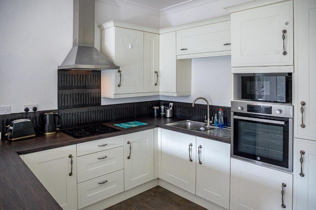 a white kitchen with white cabinets and a sink at Pass the Keys Cosy Bungalow in Sheffield in Sheffield