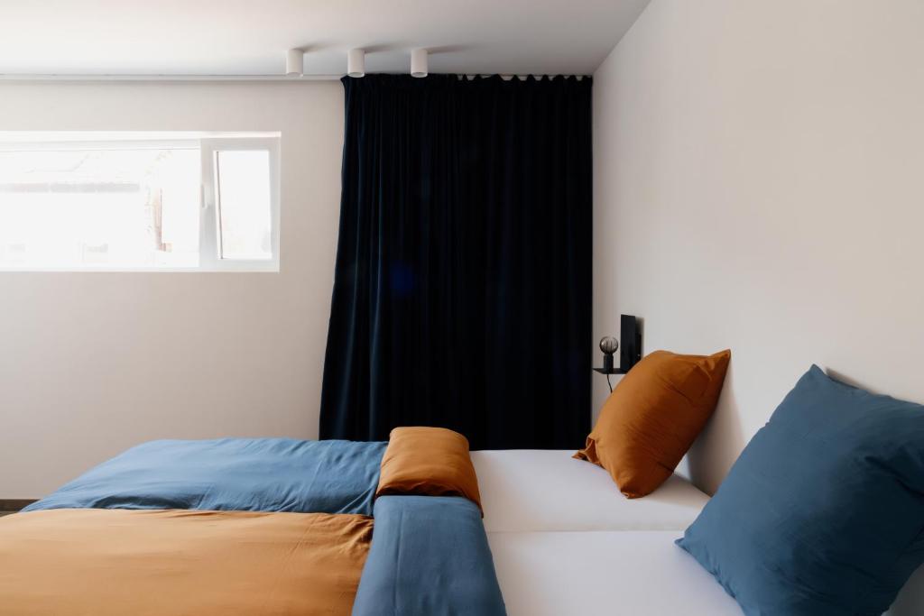 1 dormitorio con 1 cama con almohadas azules y naranjas en Befour Vakantiewoning, en Aalst