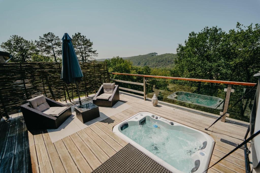 a hot tub on a wooden deck with an umbrella at Le Fruit du Chêne in Hamoir
