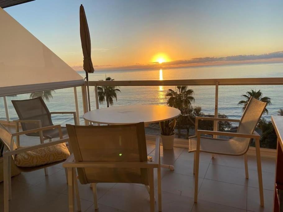 einen Tisch und Stühle auf einem Balkon mit Blick auf den Sonnenuntergang in der Unterkunft EUREKA Sea Views & Comfort in Cala Millor