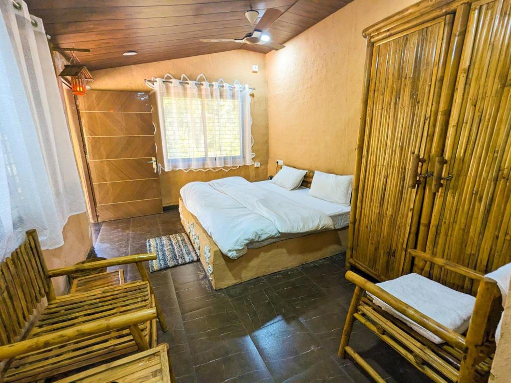 1 dormitorio con 1 cama y 2 sillas en Athulyam Kanha, kanha national park, mukki gate, en Khāpa