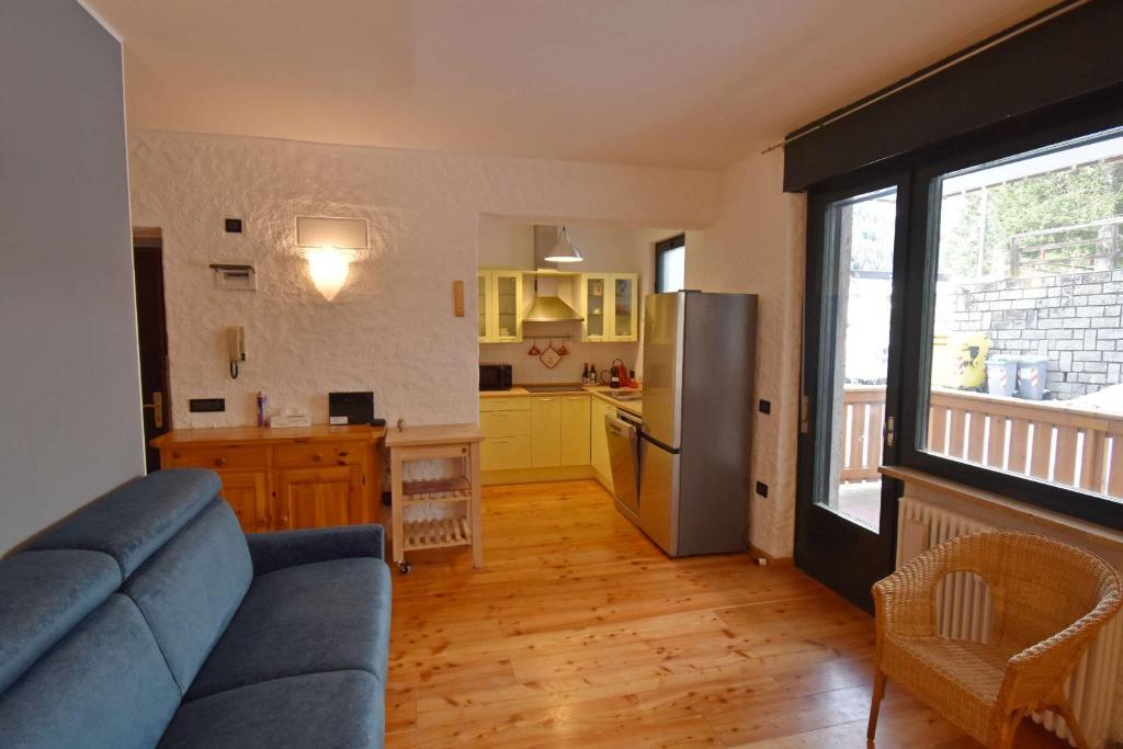 a living room with a blue couch and a kitchen at SISSI Apartment in Madonna di Campiglio