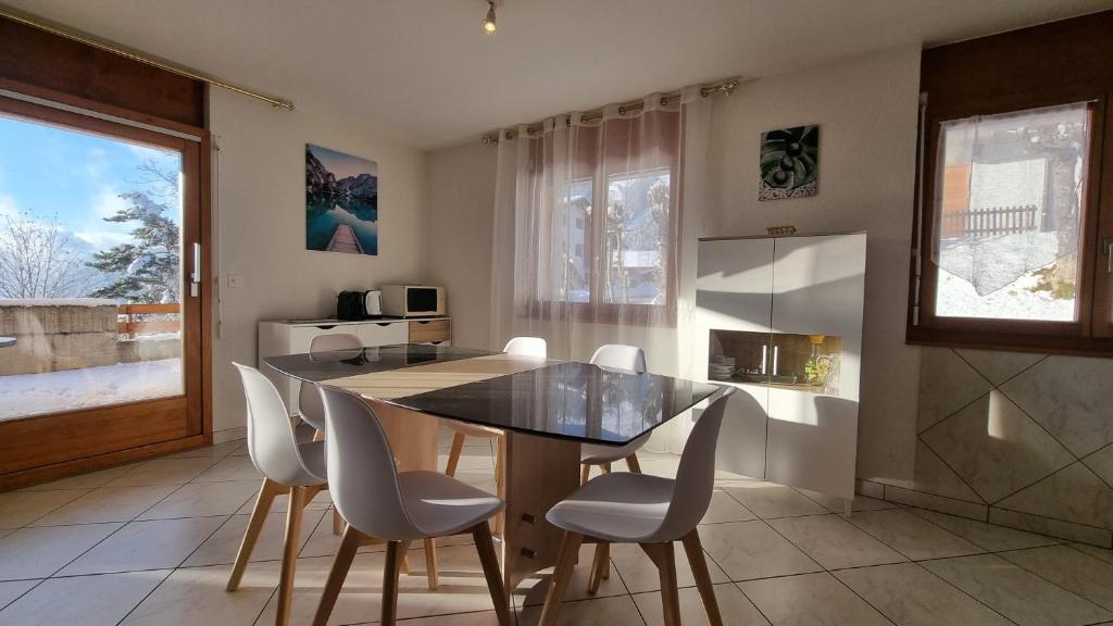 a kitchen with a dining room table and white chairs at Le Cormier - Appartement 6 personnes in Ovronnaz