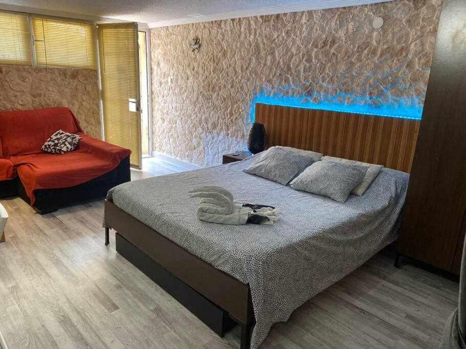 um quarto com uma cama e uma cadeira vermelha em Loft en planta baja con terraza frente al MAR em El Campello