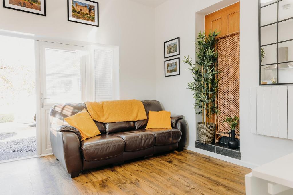 a living room with a brown leather couch with yellow pillows at Superb Tiny Home in Caldicot with Parking in Caldicot