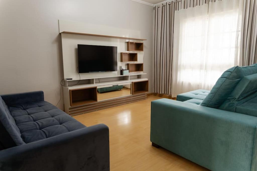 a living room with two blue couches and a television at Casa para 6 pessoas in Bento Gonçalves