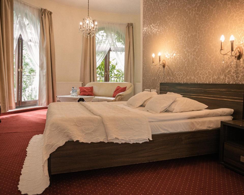 a bedroom with a large bed and a chandelier at Hotel Korona in Rybnik