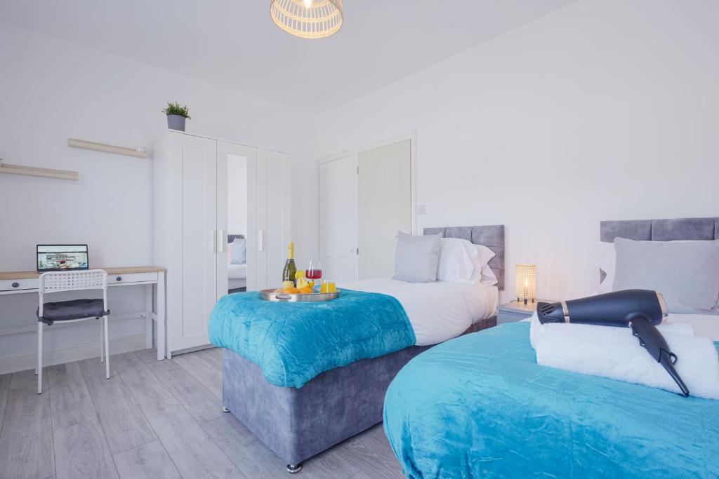 a bedroom with two beds and a desk with a desk at Newly Refurbished House - Close to Town Centre -Free Parking, Super-Fast Wifi, Smart TV with Netflix by Yoko Property in Northampton