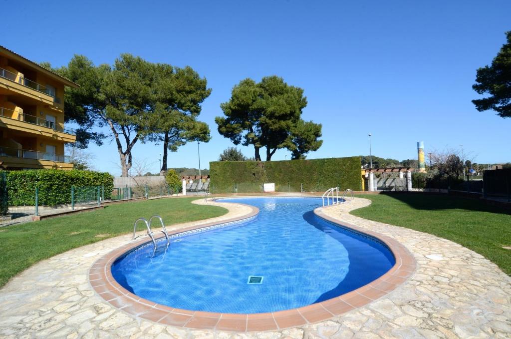 une piscine dans un parc avec des arbres en arrière-plan dans l'établissement Apartamentos Athenea, à Ampurias