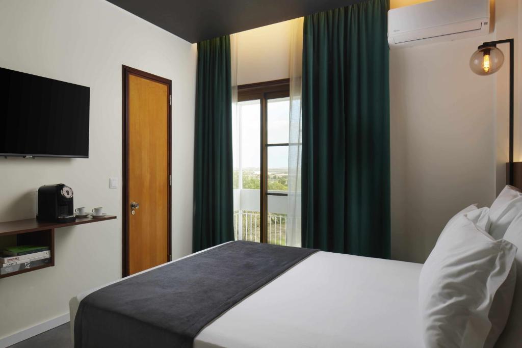 Habitación de hotel con cama y ventana en Alto House Faro AL de Assinatura Modernista en Faro