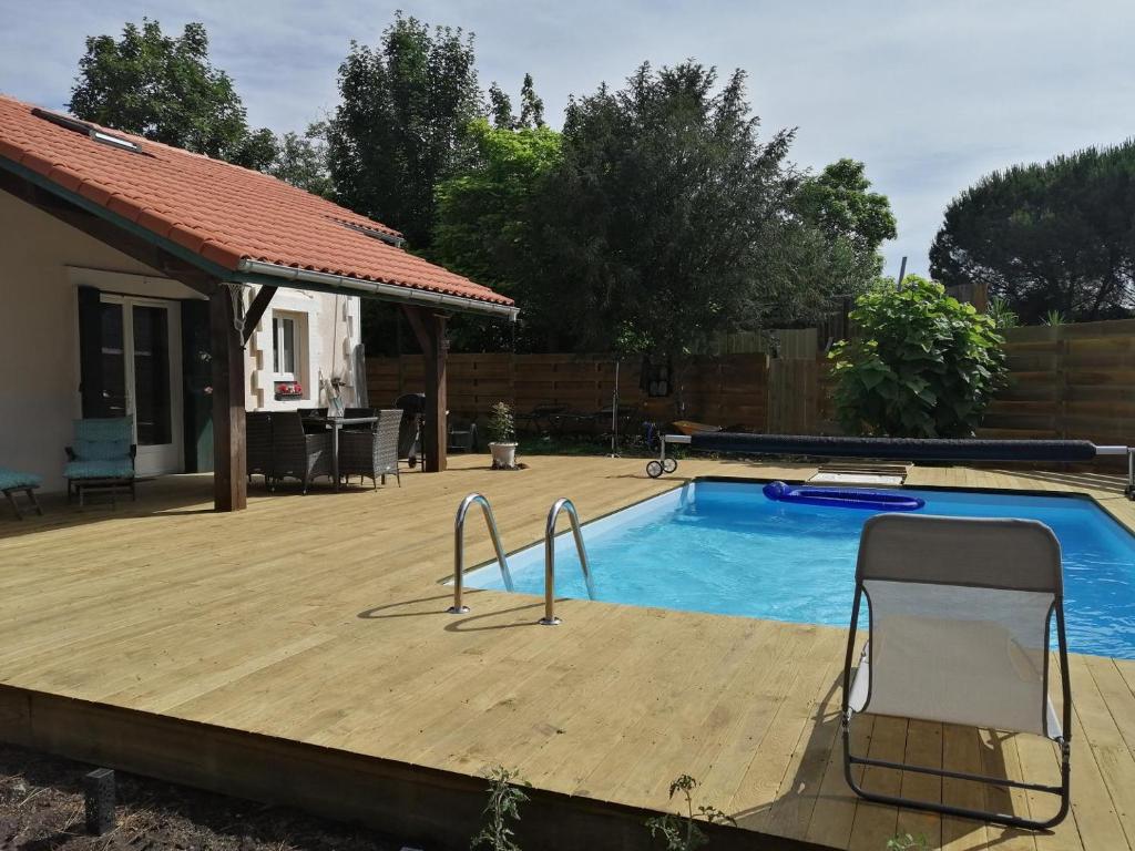 a swimming pool with a wooden deck next to a house at Gîte de linxe in Linxe