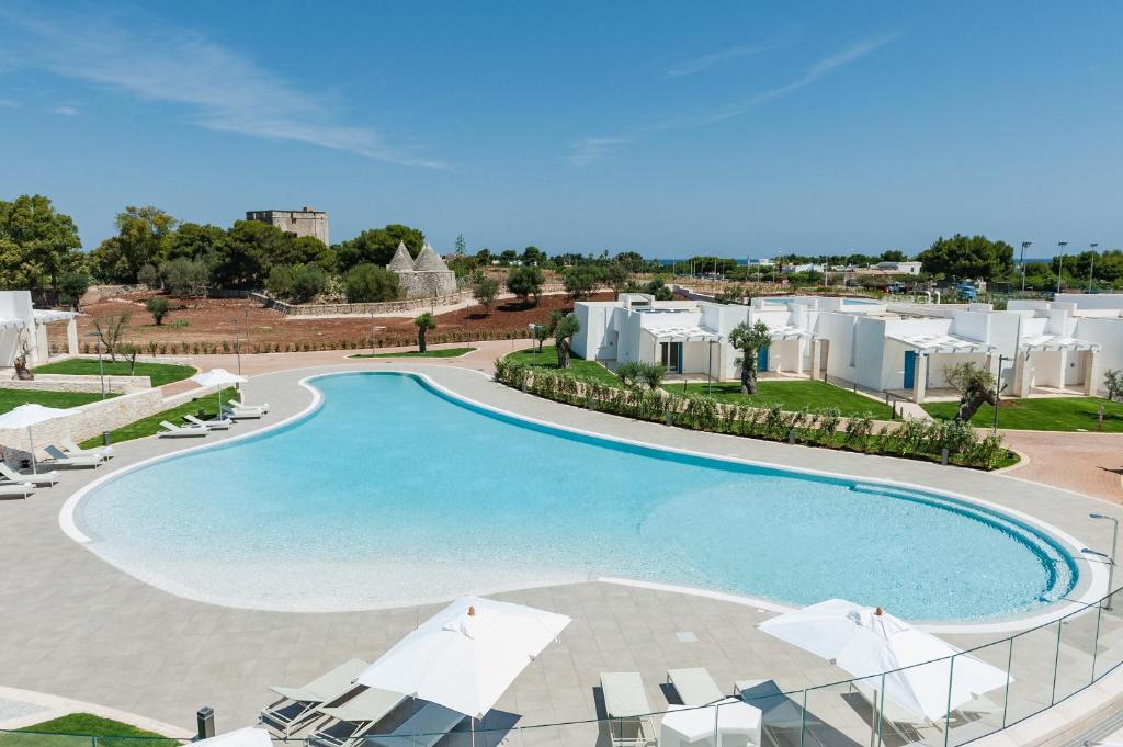 einen Blick über einen Pool mit Stühlen und Gebäuden in der Unterkunft Cala Ponte Hotel in Polignano a Mare