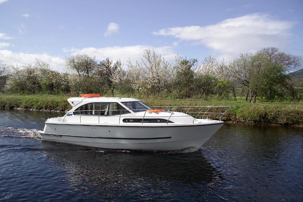 a white boat in the water on a river at Caley Cruisers in Inverness
