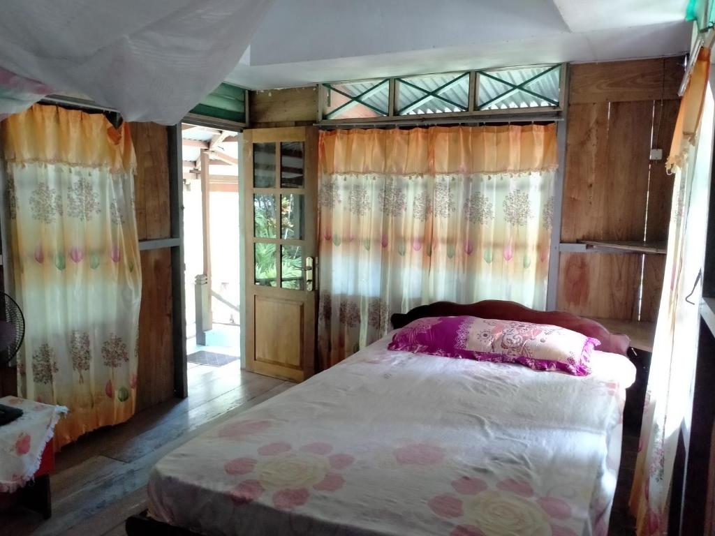 a bedroom with a bed in a room with curtains at Delima Cottage, Ngurbloat Beach in Ngurblut