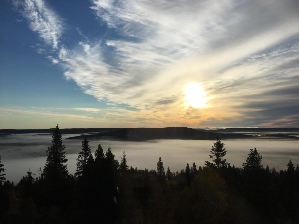 een zonsondergang boven een waterlichaam met bomen bij Peipon pesä in Syöte