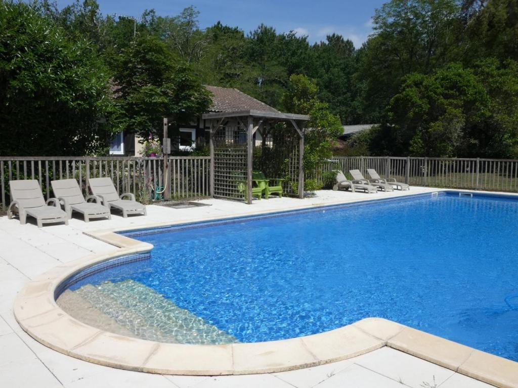 a swimming pool with chairs and a gazebo at Au gat in Léon