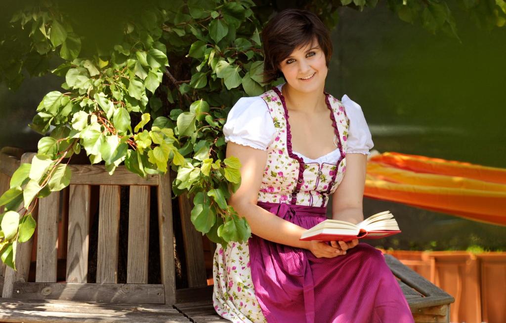 una mujer sentada en un banco sosteniendo un libro en Zum goldenen Engel - Fam. Ehrenreich, en Krems an der Donau