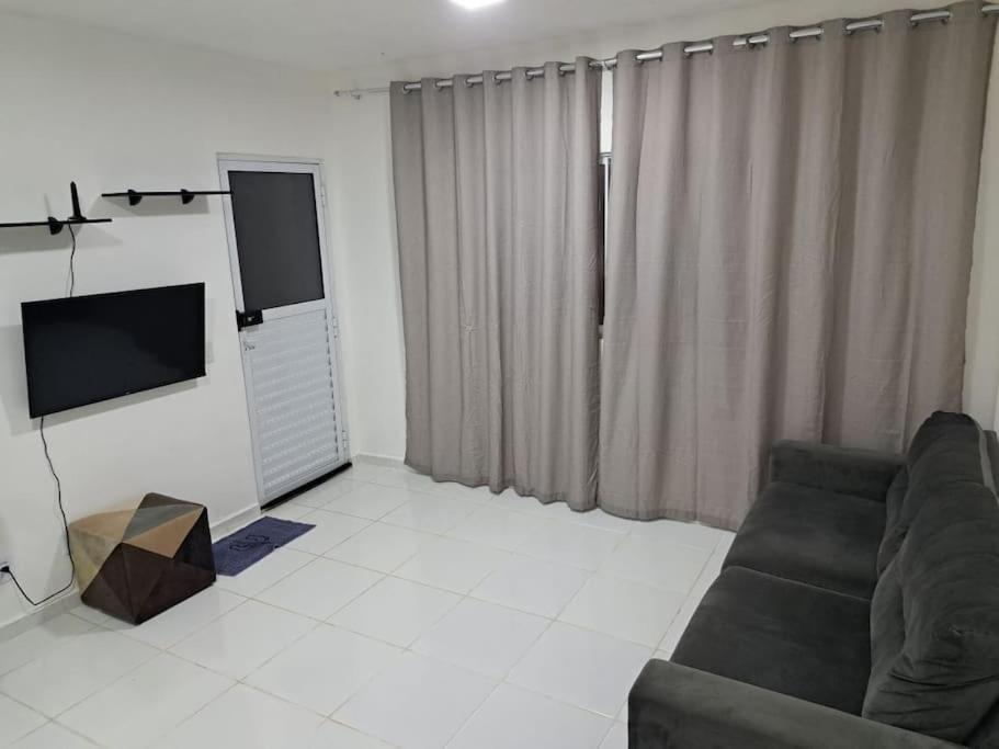 a living room with a couch and a flat screen tv at Apartamento no Condomínio Roma com estacionamento in Pôrto Santana