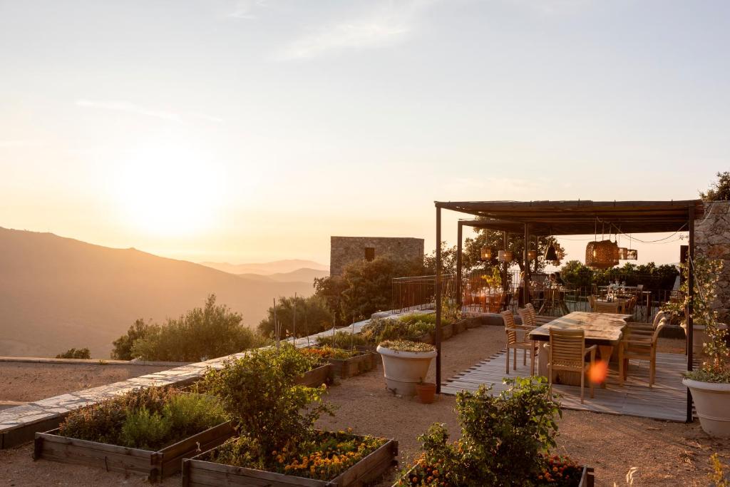 a garden with a table and chairs and the sunset at Hôtel Case Latine in Lama