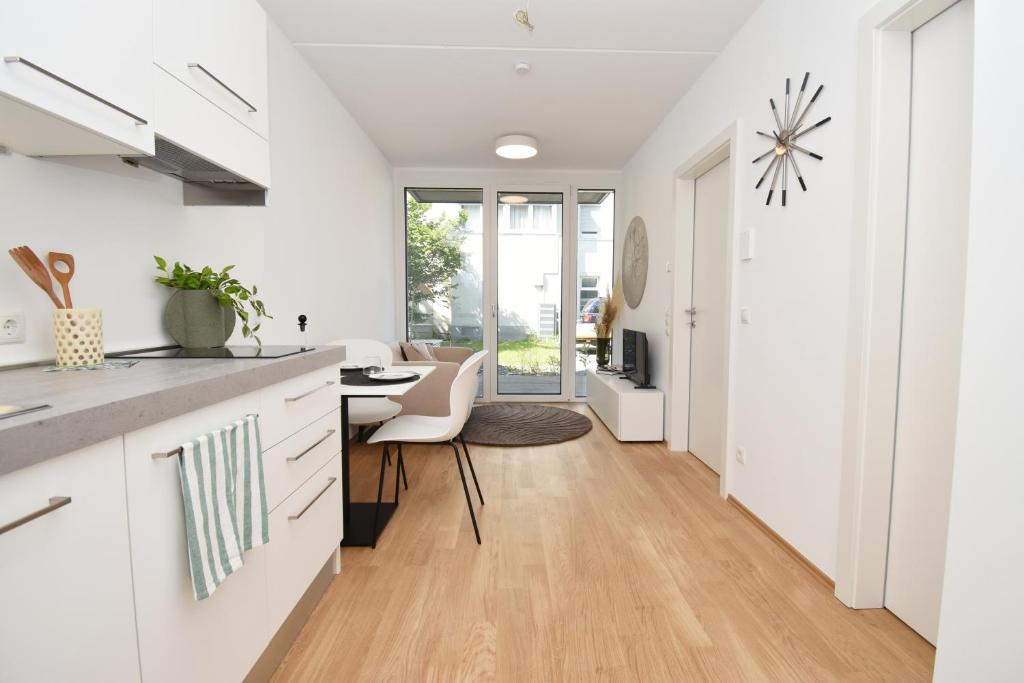 a kitchen with white cabinets and a dining room with a table at Ferienwohnung in Hard am Bodensee in Hard
